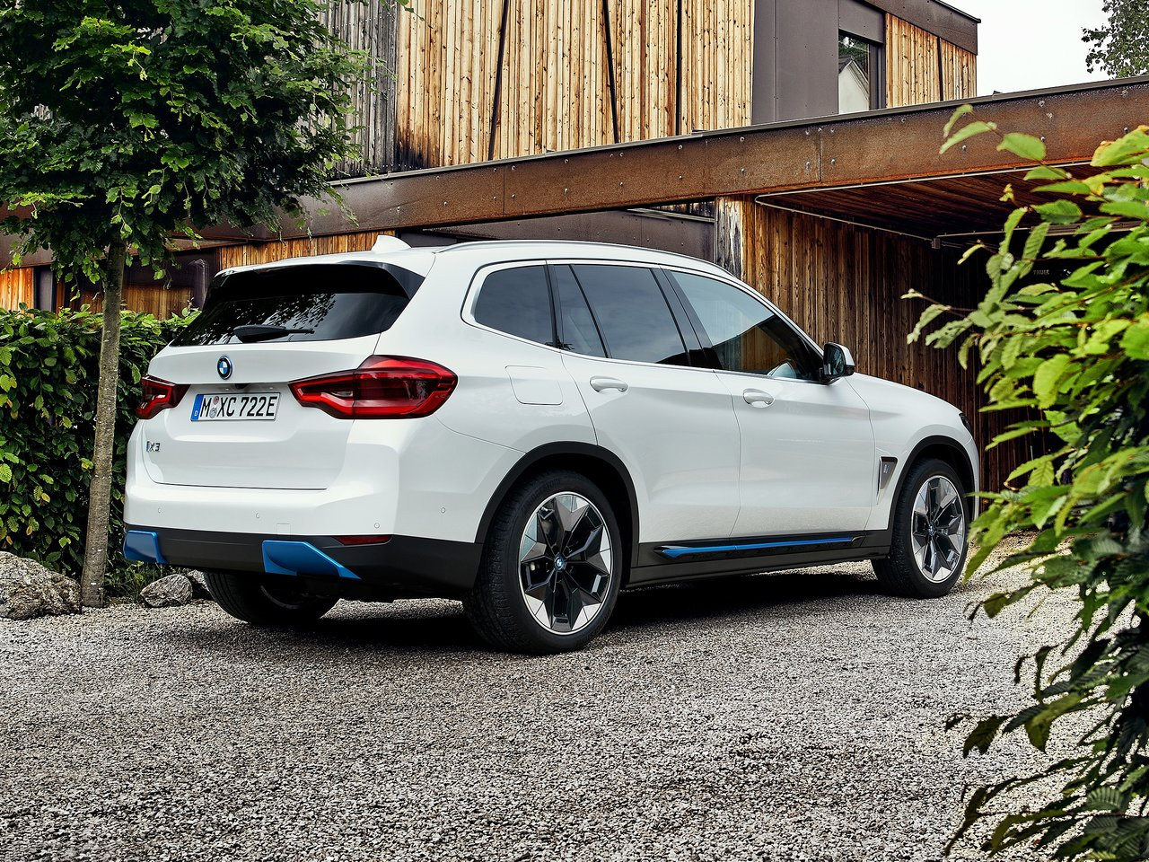 Rear view of a BMW iX3 parked on a gravel driveway